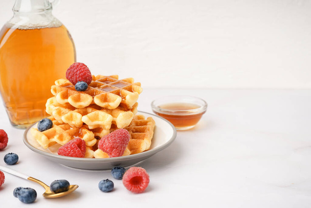 Тарелка вкусных вафель с ягодами и кленовым сиропом на белом фоне - Фото, изображение