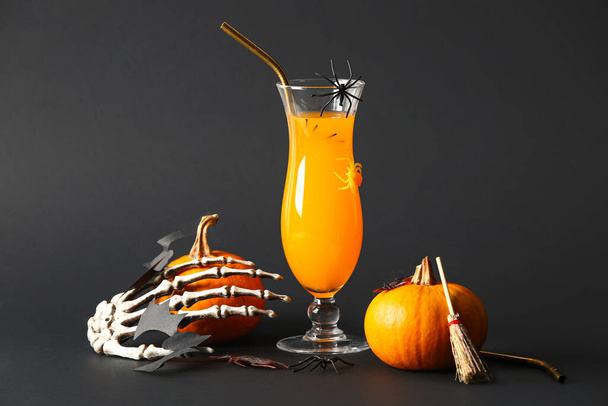 Szklanka pysznego pomarańczowego koktajlu, ręka szkielet i dynie na Halloween uroczystości na czarnym tle - Zdjęcie, obraz