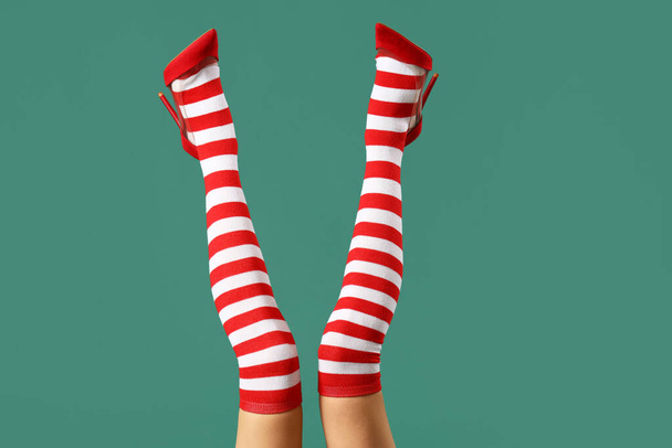 Young woman in Christmas stockings on green background - Photo, Image