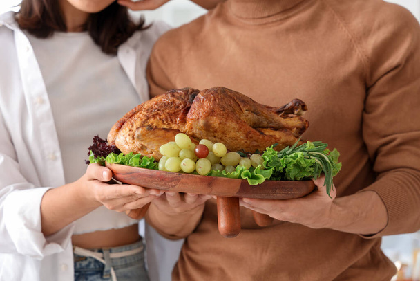 Jeune couple avec dinde savoureuse à la maison le jour de Thanksgiving, gros plan - Photo, image