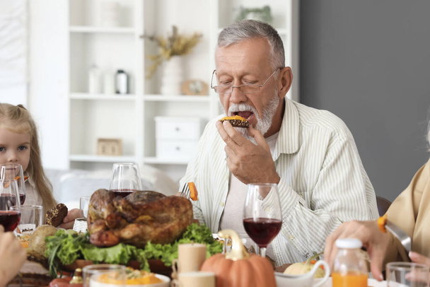 Volwassen man met familie diner aan feestelijke tafel op Thanksgiving Day - Foto, afbeelding