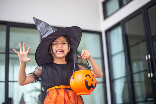 Boldog ázsiai kislány boszorkányjelmezben Halloweenkor. Csokit vagy csalunk. Csokit vagy csalunk.. - Fotó, kép