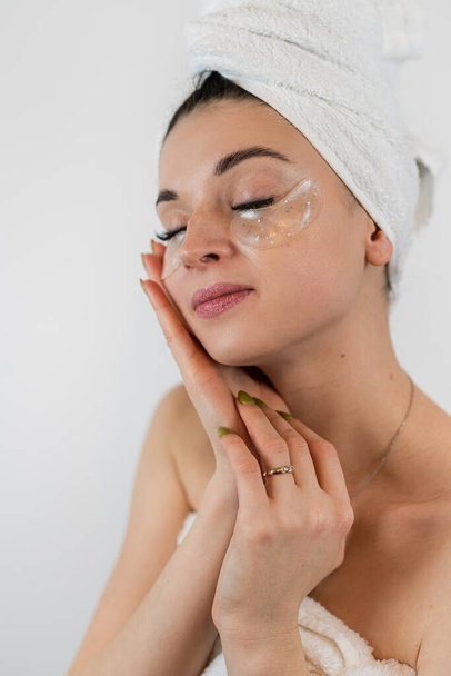 giovane donna con macchie oculari idrogel isolato su bianco, procedura facciale per ridurre l'edema e ringiovanire, concetto di cura della pelle - Foto, immagini