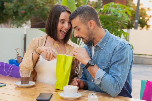 sprzedaż, zakupy, konsumpcjonizm, rozrywka i koncepcja ludzi - szczęśliwa para z torbami na zakupy pijąca kawę w centrum handlowym - Zdjęcie, obraz
