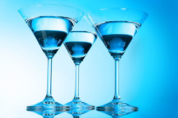 Three martini glasses on blue background - Фото, изображение