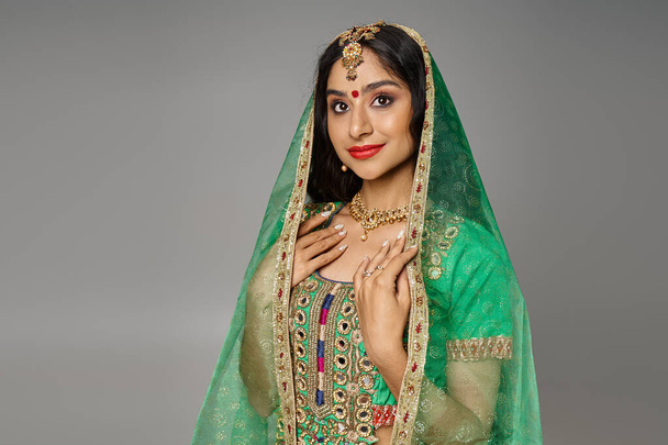 schöne Indianerin mit Bindi auf der Stirn in Tracht und grünem Schleier schaut in die Kamera - Foto, Bild