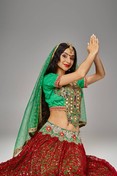 tiro vertical de jovem mulher indiana alegre em traje nacional com bindi dot olhando para a câmera - Foto, Imagem