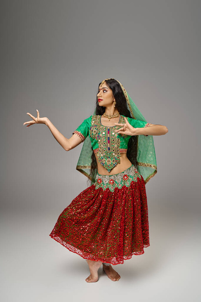 Geleneksel giysiler içinde dans ederken el kol hareketi yapan Hintli çekici kadının dikey çekimi. - Fotoğraf, Görsel