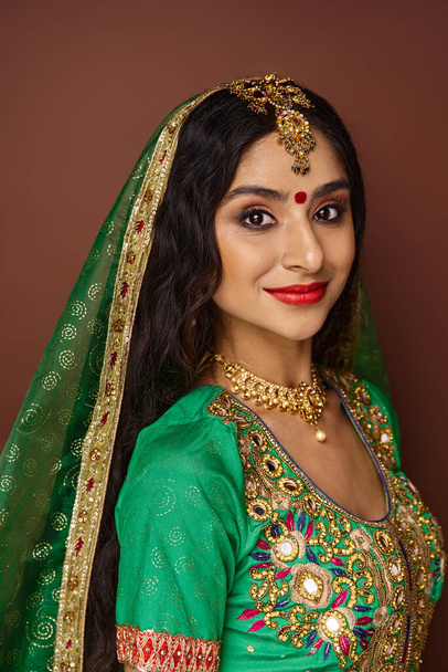 atractiva mujer india con punto bindi en la frente y accesorios tradicionales sonriendo a la cámara - Foto, imagen