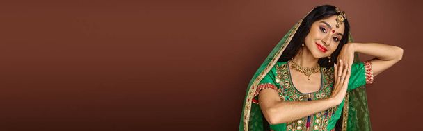 όμορφη νεαρή Ινδή γυναίκα σε εθνικό φορούν gesturing και χαμογελώντας ευτυχισμένα στην κάμερα, πανό - Φωτογραφία, εικόνα