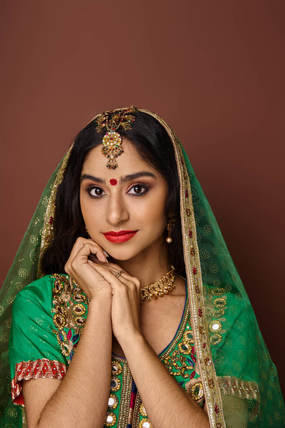 verticaal schot van mooie indische vrouw met groene sluier en bindi stip op het voorhoofd kijken naar camera - Foto, afbeelding
