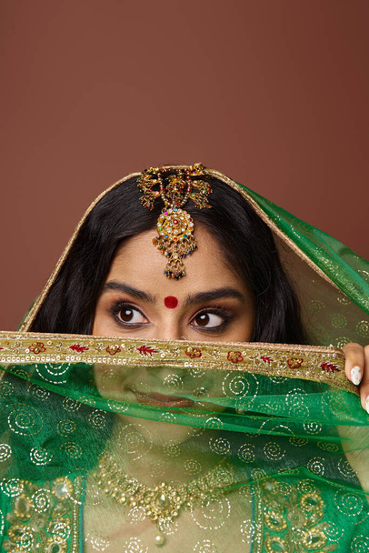 Güzel Hintli kadının dikey görüntüsü Bindi noktasıyla yüzünü örtüyor ve başka yere bakıyor. - Fotoğraf, Görsel