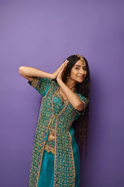 belle femme indienne aux cheveux longs en vêtements nationaux posant en mouvement et regardant la caméra - Photo, image