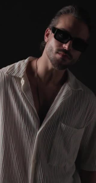 sexy lässiger junger Mann mit Sonnenbrille zur Seite blickend und sinnlich vor rotem und blauem Lichterhintergrund - Filmmaterial, Video