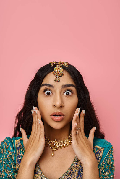 überraschte junge Indianerin in Tracht posiert mit den Händen vor dem Gesicht mit offenem Mund - Foto, Bild