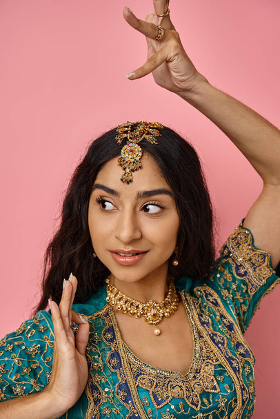 attraktive, fröhliche junge Indianerin in Tracht gestikuliert beim Tanzen und schaut weg - Foto, Bild