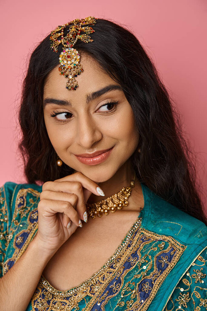 vertical shot of attractive indian woman in blue sari with accessories posing with hand on chin - Photo, Image