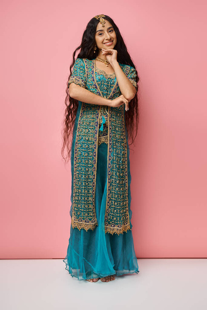 Vertikale Aufnahme einer indischen Frau in traditioneller Kleidung, die mit der Hand unterm Kinn in die Kamera lächelt - Foto, Bild