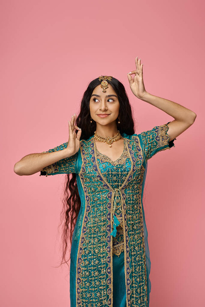 pionowe ujęcie młodej hinduskiej kobiety w tradycyjnej odzieży z akcesoriami aktywnie gestykulującymi - Zdjęcie, obraz