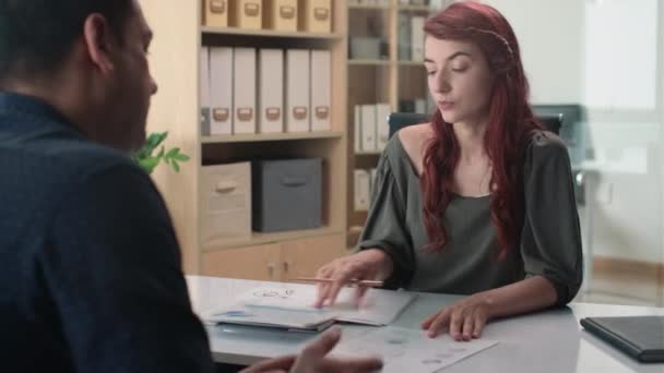Середній знімок молодої жінки, що розмовляє з бізнесменом про результати звіту в офісі - Кадри, відео