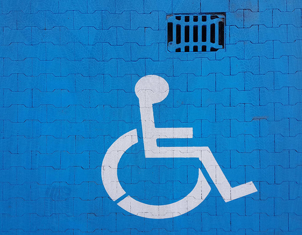 Señal de señalización vial sobre un fondo azul que indica estacionamiento para un vehículo discapacitado. La conveniencia de aparcar un vehículo. El viaje de las personas con discapacidad en silla de ruedas. Espacio libre para los necesitados
. - Foto, imagen