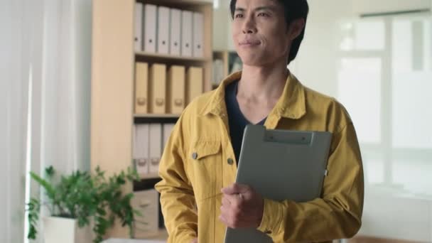 Kallista muotokuvaa aasialaisesta yrittäjästä, jolla on hallussaan asiakirja ja katsot kameraa - Materiaali, video