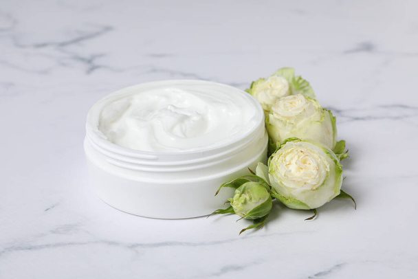 Jar with cream and roses on marble background, close up - Photo, Image