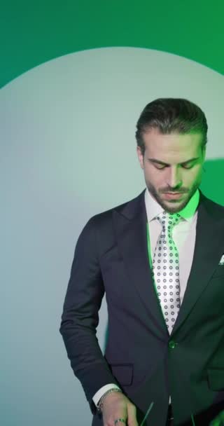 sexy bebaarde zakenman naar beneden en opzij kijken, zetten bril op, het houden van handen in zakken in de voorkant van kleurrijke achtergrond - Video
