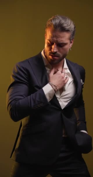 handsome cool man looking down, pulling and adjusting shirt and suit, smiling and being confident, holding hand in pocket and moving to side on colorful background - Footage, Video