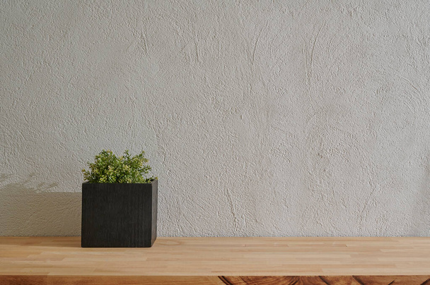 Βάζο του φυτού μπροστά από το γκρίζο πέτρινο τοίχο, ξύλινο τραπέζι. - Φωτογραφία, εικόνα
