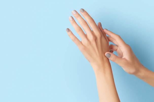 Женские руки с серым дизайном ногтей на синем фоне. Тенденции маникюра, педикюра - Фото, изображение