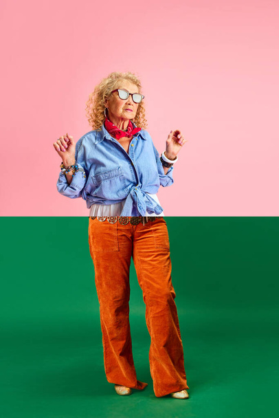緑色のピンクの背景に立っている異なるスタイリッシュな服のシニア女性の画像の半分で作られたコラージュ. 多様性について。 感情,ファッション,高齢者,ライフスタイル,創造性の概念. アドベンチャー - 写真・画像