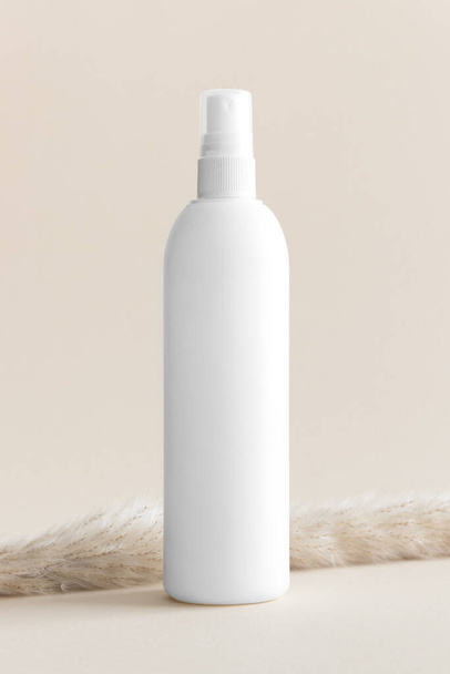Біла косметична пляшка для розпилення маскування на м'якому жовтому фоні. - Фото, зображення