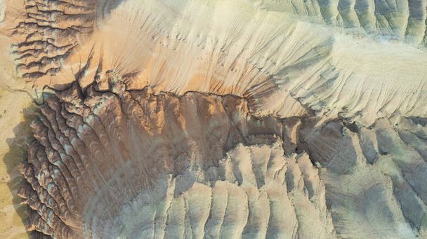 Alte montagne colorate e un canyon di argilla. Una grande gola con rocce diverse e colori diversi. Fiori rossi, arancioni, bianchi e gialli delle pareti delle rocce. Un turista cammina. Aktau - Foto, immagini
