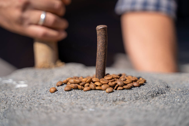 Koffiebonen in een traditionele steenmolen. - Foto, afbeelding