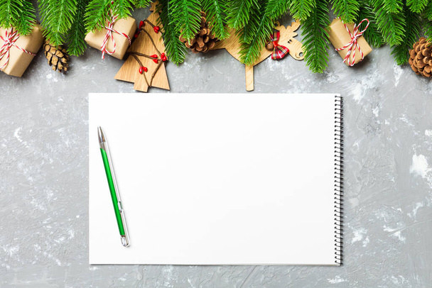 Top view of a notebook on cement holiday background made of fir tree and New Year decorations. Christmas time concept. - Photo, Image