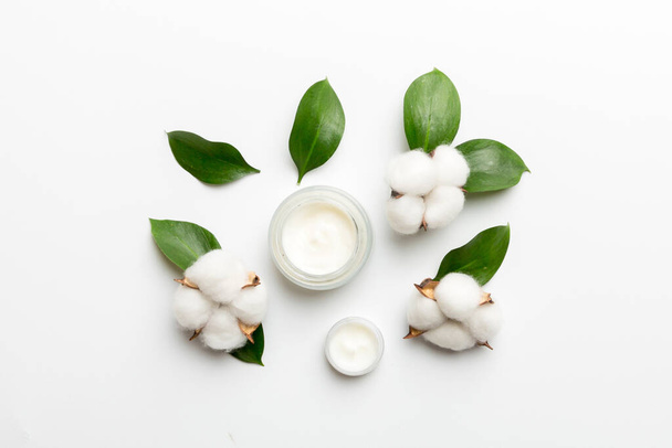 Produits cosmétiques bio avec fleur de coton et feuilles vertes sur fond blanc. Pose plate. - Photo, image