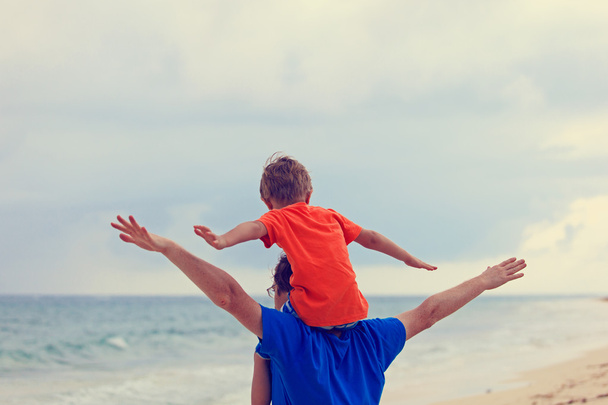 счастливые отец и сын играют на морском пляже
 - Фото, изображение