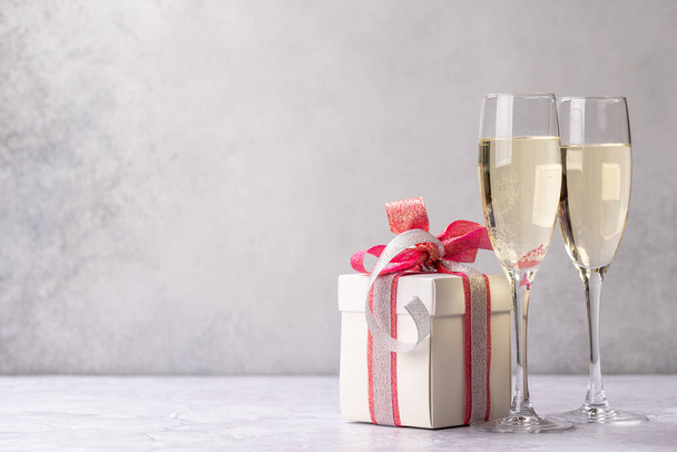 Two champagne glasses and gift box. Christmas greeting card template with copy space - Photo, Image