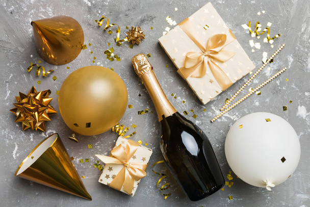 Flat lay composition of Champagne bottle gift box ribbons and confetti on colored background. Flat lay, top view holiday concept. - Photo, Image