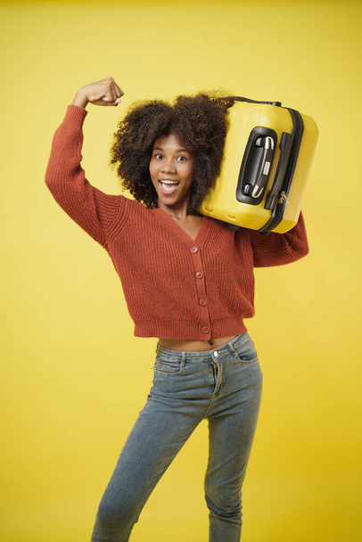 Afrikai amerikai fiatal nő alkalmi életmód sárga poggyász úgy néz ki, izgalmas és készen áll az utazásra, utazás egyedül, nő felfedezni, magabiztos. - Fotó, kép