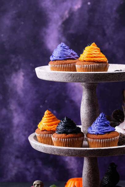 黒、紫、オレンジのクリームと装飾が施されたハロウィンカップケーキ - 写真・画像