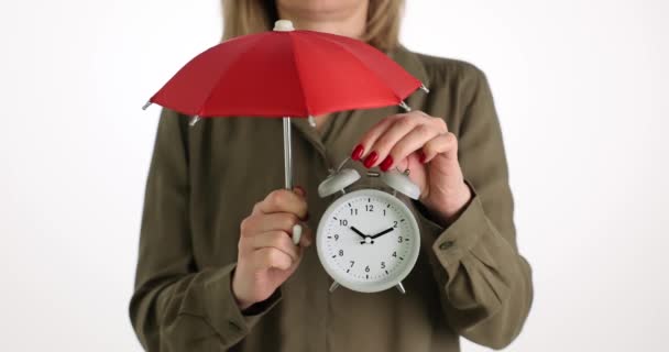 Nainen pitelee herätyskelloa sateenvarjo lähikuva 4k elokuva. Ajan arvon käsite - Materiaali, video