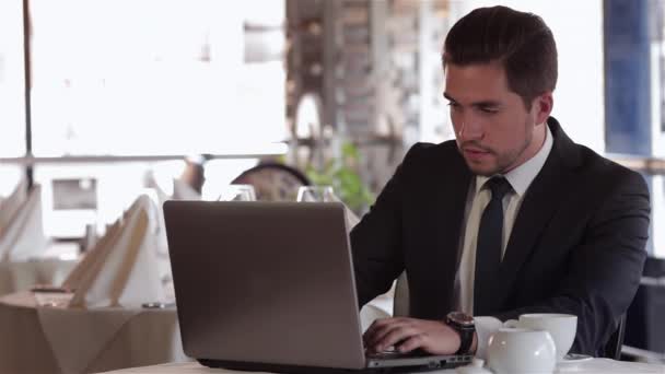 Business lunch in a restaurant, cafe, coffee shop. Casual dressed young businessman eating at a table in a cafe, restaurant, coffee shop. The male uses a tablet. - Footage, Video