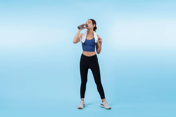 Atletische en sportieve Aziatische vrouw rusten en drinken water na intensieve cardiotraining. Gezond sporten en fit lichaamsverzorging levensstijl streven in studio shot geïsoleerde achtergrond. Krachtig - Foto, afbeelding