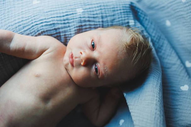 Een close-up van het gezicht van een pasgeboren baby. Een pasgeborene kijkt naar de camera. Open ogen van een pasgeboren baby - Foto, afbeelding