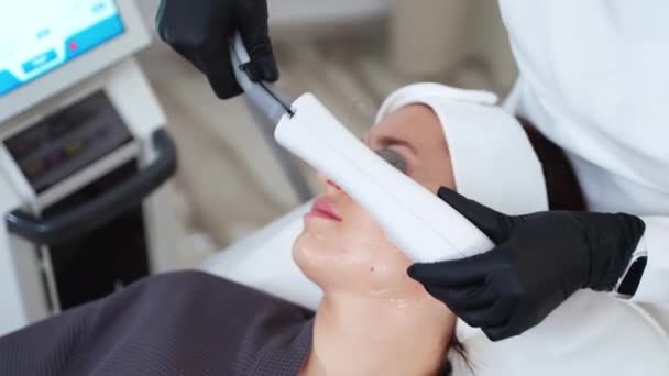 Kosmetolog zapewniający leczenie twarzy w klinice medycyny estetycznej i wykorzystujący laser BBL do fotorejuvenacji skóry. Laser leczy zaczerwienienie, uszkodzenia słoneczne, dając efekt anti-aging - Materiał filmowy, wideo