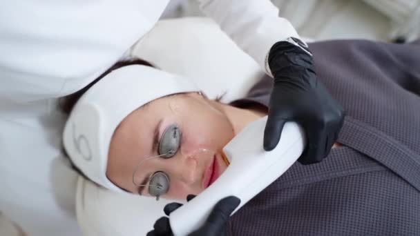 Kobieta leczona laserem BBL w klinice kosmetologii. Leczenie przeciwstarzeniowe, zwalczanie trądziku i plam słonecznych, depilacja - Materiał filmowy, wideo