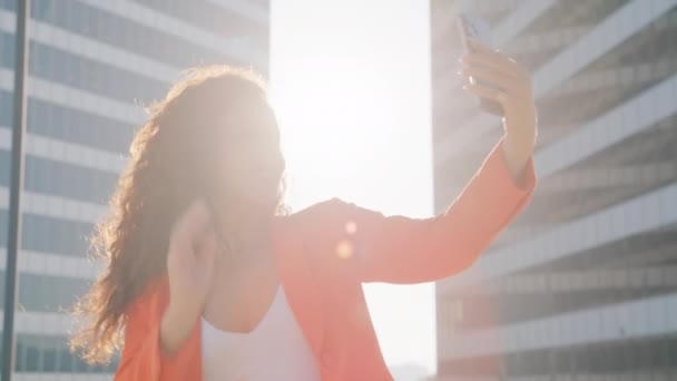 Glückliche Frau mit zwei Rassen, die ein Selfie macht und in den sozialen Medien Apps postet, die in der Innenstadt in goldenem Sonnenschein stehen. Fashion Lifestyle Influencer Blogger mit Handy online - Filmmaterial, Video