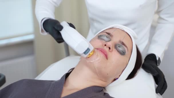 Kozmetikai eljárásokon áteső nő, akit agyag lézerrel látnak el. Arckezelés, a bőr állapotának javítása a kozmetikai klinikán - Felvétel, videó